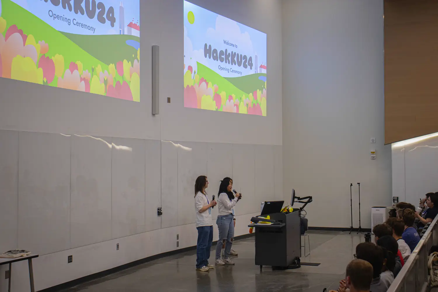 The organizers present us their slideshow at opening ceremonies. The current slide says "HackKU" and prominently displays the event's branding.