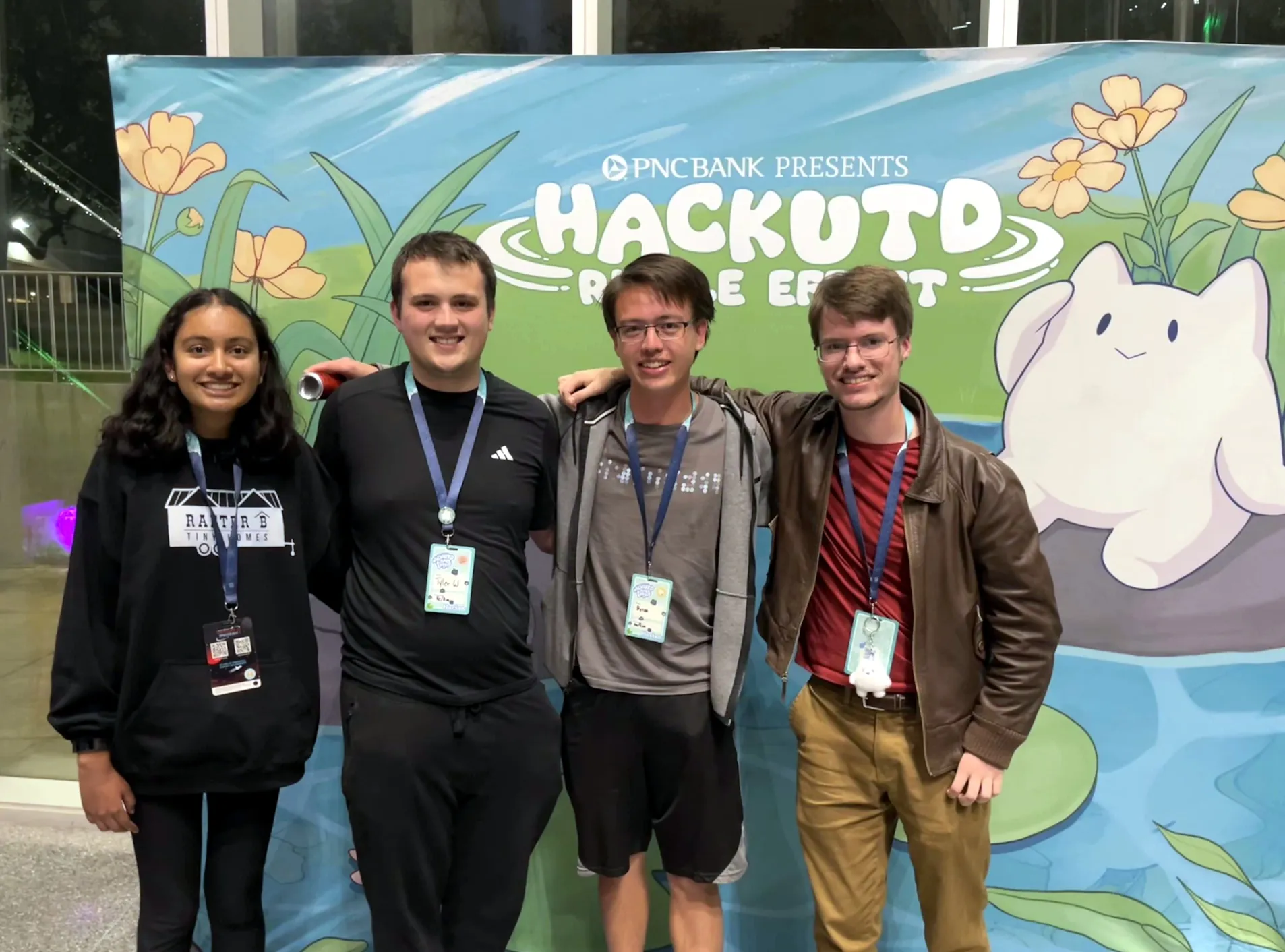 My team poses in front of a HackUTD banner. I discretely hold an energy drink in my right hand.