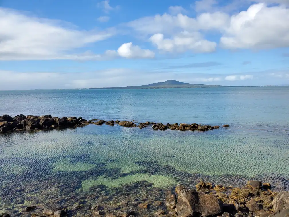 view of Rangitoto Island from Takapuna with shallow rocky pool in foreground