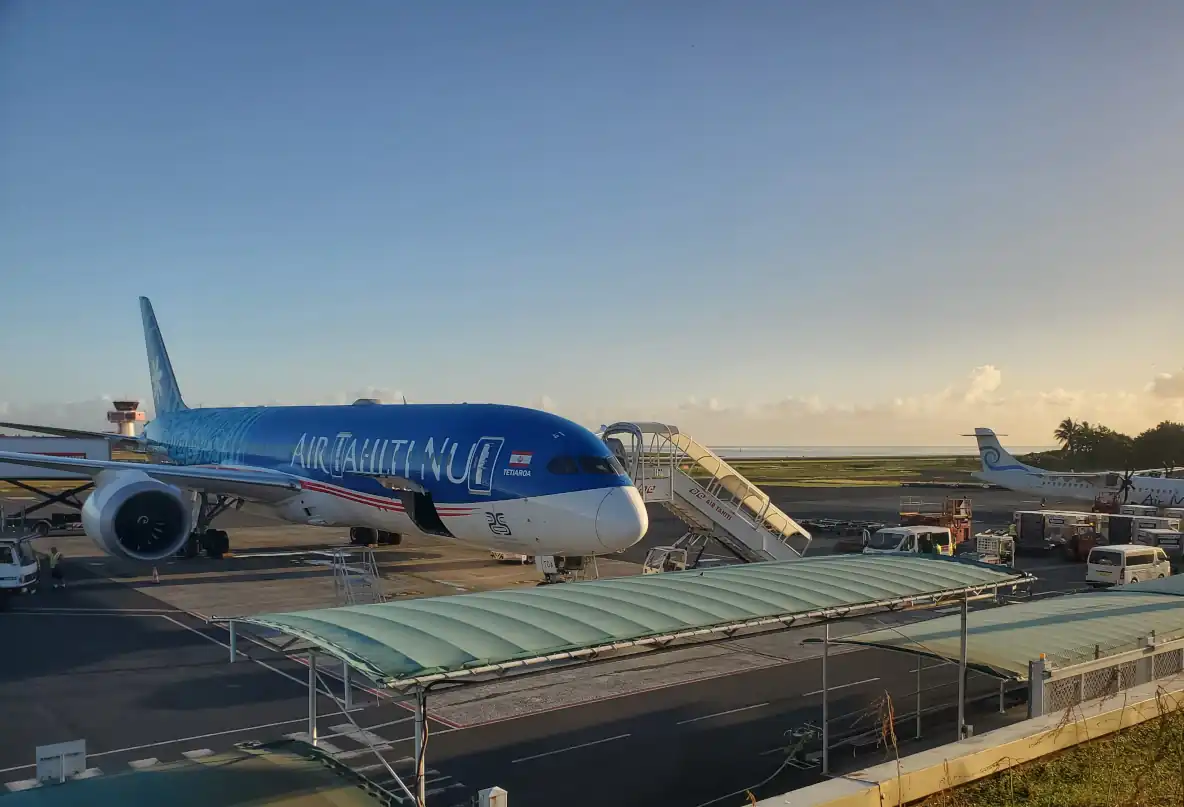 a Boeing 787 in Air Tahiti Nui livery parked on the airport tarmac at sunrise